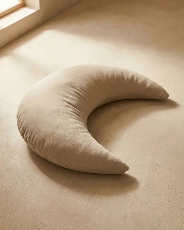 The Cove Mini in Oat, a small plush crescent on a warm plaster floor